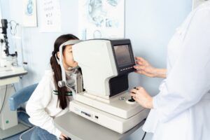 Criança num consultório de oftalmologia, a fazer um exame aos olhos.